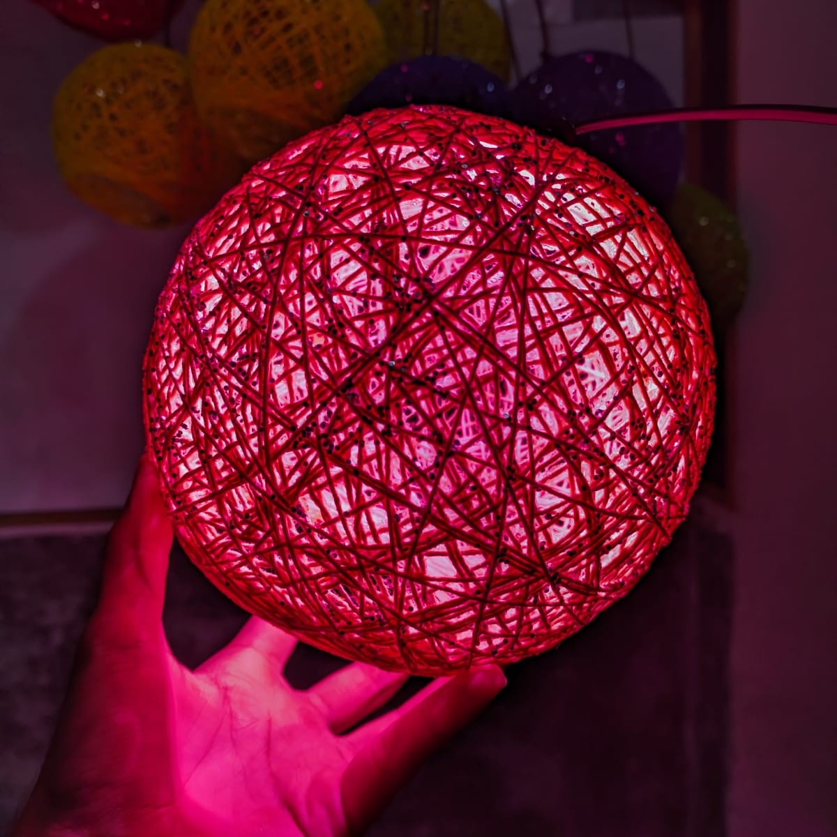 String ball lamp showing its decorative colour design, with colours supplied randomly.