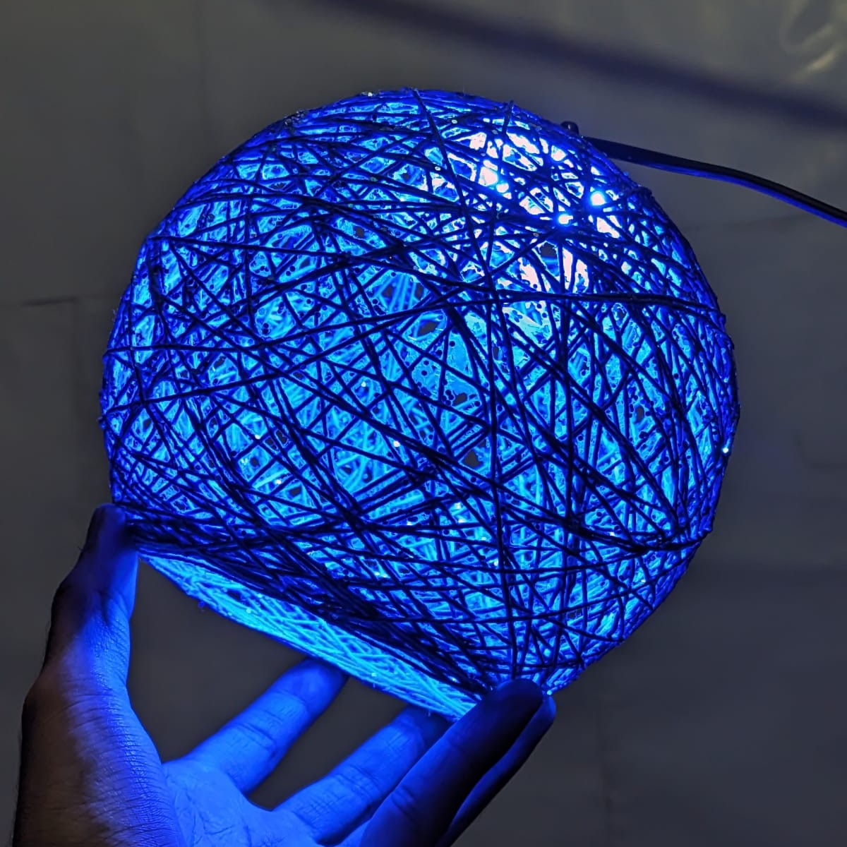 String ball lamp used as a decorative lighting accessory in a bedroom.
